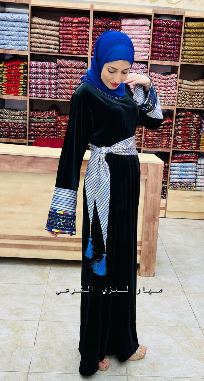 Black abaya with blue and white details and belt.