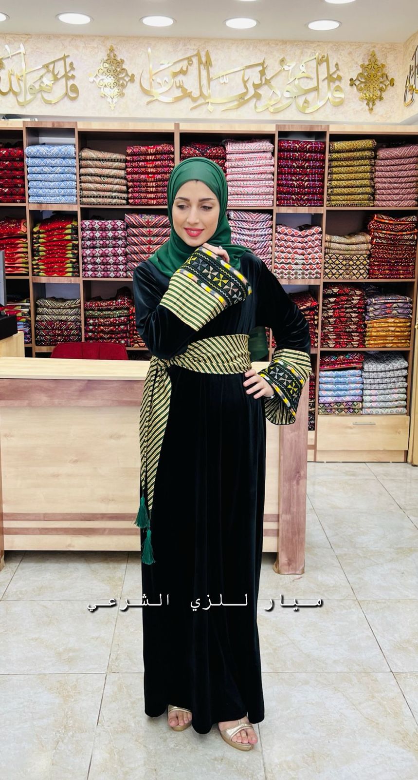 Black abaya with green and white details and belt.