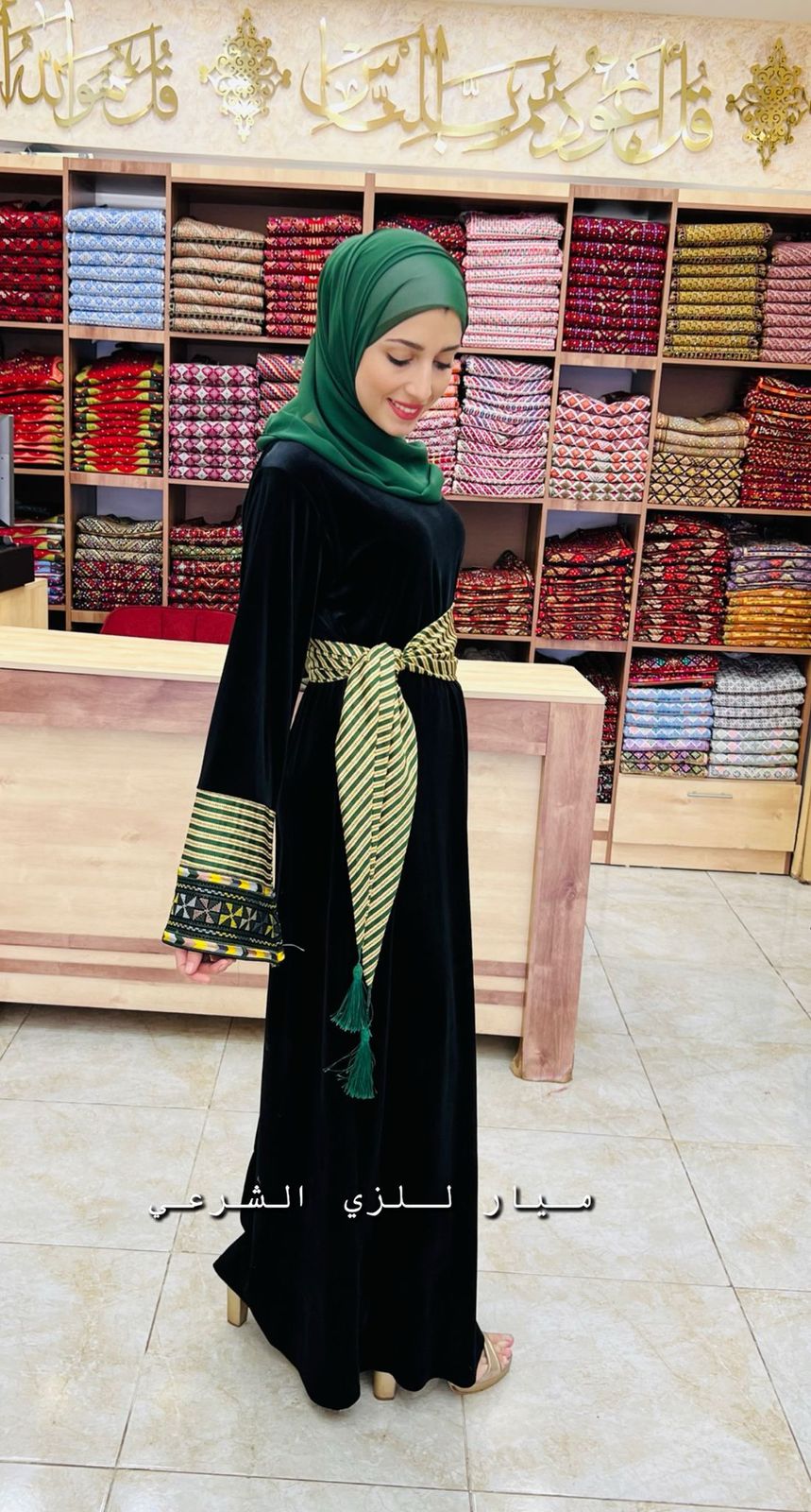 Black abaya with green and white details and belt.